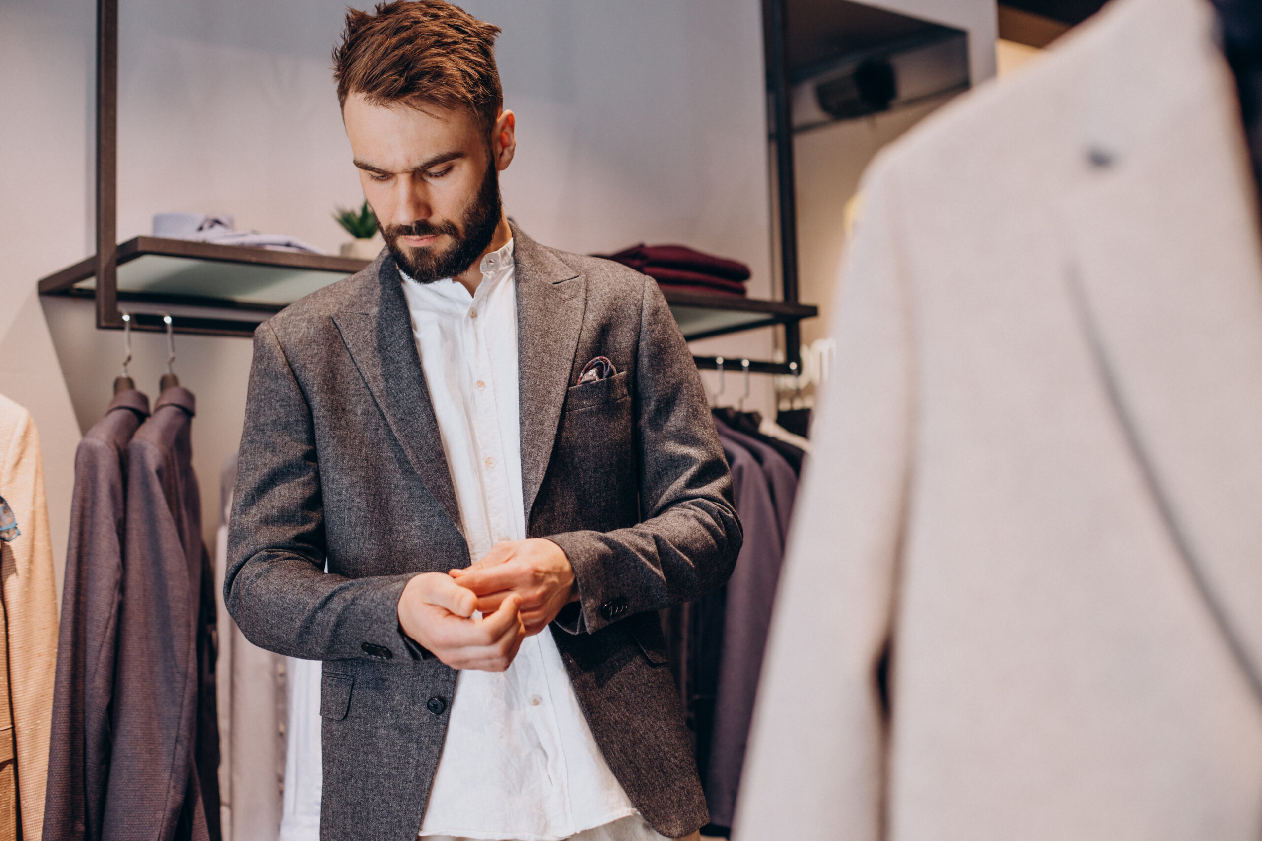 Young man choosing cloths in menswear shop